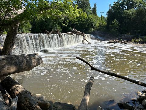 The Ossipee Mill Dam spanning Reedy Fork near Burlington, NC, with water flowing over the full width of the dam